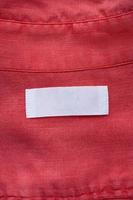 White blank clothing tag label on red linen shirt fabric texture background photo