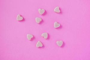 valentine candy hearts shape on pink background photo