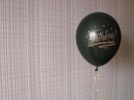 Black balloon with words HAPPY BIRTHDAY on yellow background, space for text photo