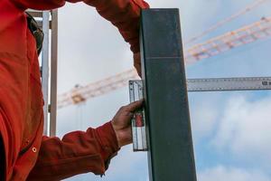 A skilled worker measures and marks a line on a square pipe with an iron ruler for further cutting photo