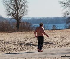 Dnepr, Ukraine - 02.21.2022 A middle-aged man does gymnastics on the river bank. The concept of a healthy lifestyle and the fight against line weight. photo