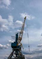 Large tower cranes stand in a river port against a cloudy sky. photo