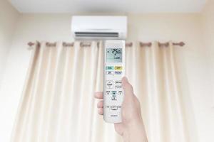 woman holding air conditioner remote control with air conditioner in bedroom photo