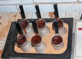 Traditional Turkish coffee with foam in cezve prepared on hot sand in authentic Turkish Copper or coffee machine. photo