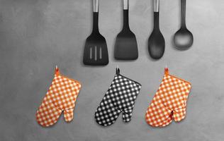 Orange Heat Resistant Cooking Gloves Black with kitchen utensils hanging on cement wall. photo