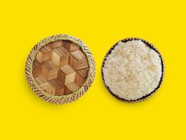 Traditional patterned bamboo box with Thai sticky rice on yellow background. photo