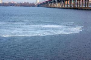 Thin ice floe drifts downstream in springtime photo