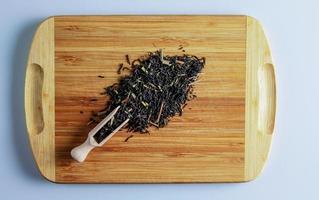 The tea is ready to be brewed. Spatula for brewing tea. Background of fragrant black tea leaves with lemon grass. photo