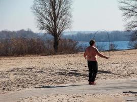 Dnepr, Ukraine - 02.21.2022 A middle-aged man does gymnastics on the river bank. The concept of a healthy lifestyle and the fight against line weight. photo