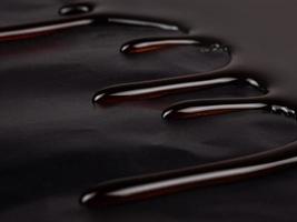 drops of chocolate caramel on a dark background, hot caramel syrup closeup photo