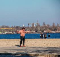 Dnepr, Ukraine - 02.21.2022 A middle-aged man does gymnastics on the river bank. The concept of a healthy lifestyle and the fight against line weight. photo