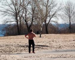 Dnepr, Ukraine - 02.21.2022 A middle-aged man does gymnastics on the river bank. The concept of a healthy lifestyle and the fight against line weight. photo