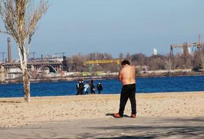 dnepr, ucrania - 02.21.2022 un hombre de mediana edad hace gimnasia en la orilla del río. el concepto de un estilo de vida saludable y la lucha contra el peso de la línea. foto