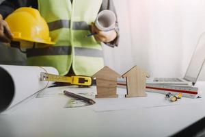 Two colleagues discussing data working and tablet, laptop with on on architectural project at construction site at desk in office photo