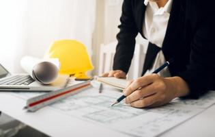 Two colleagues discussing data working and tablet, laptop with on on architectural project at construction site at desk in office photo