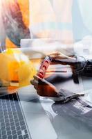 Dos colegas discutiendo el trabajo de datos y una tableta, un portátil con un proyecto arquitectónico en el sitio de construcción en un escritorio en la oficina foto