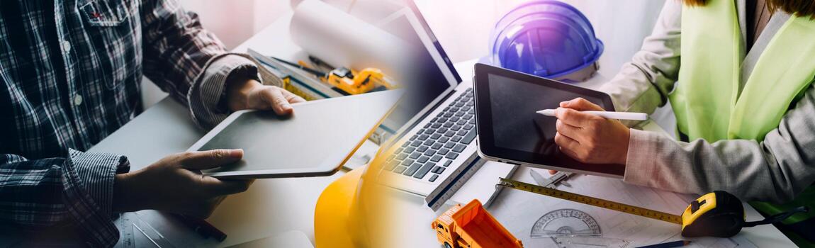 Two colleagues discussing data working and tablet, laptop with on on architectural project at construction site at desk in office photo