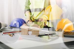 Two colleagues discussing data working and tablet, laptop with on on architectural project at construction site at desk in office photo