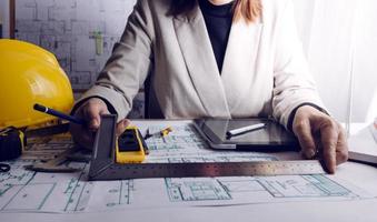 Two colleagues discussing data working and tablet, laptop with on on architectural project at construction site at desk in office photo