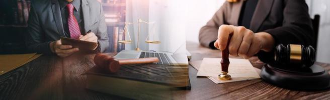 Business and lawyers discussing contract papers with brass scale on desk in office. Law, legal services, advice, justice and law concept picture with film grain effect photo