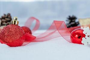 navidad de invierno - bolas de navidad con cinta en la nieve, concepto de vacaciones de invierno. bolas rojas de navidad, bolas doradas, decoraciones de pino y copos de nieve en el fondo de la nieve foto