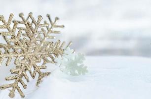 navidad de invierno - copos de nieve de navidad en la nieve, concepto de vacaciones de invierno. decoraciones de copos de nieve blancos y dorados en el fondo de la nieve foto