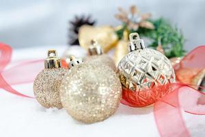 navidad de invierno - bolas de navidad con cinta en la nieve, concepto de vacaciones de invierno. bolas rojas de navidad, bolas doradas, decoraciones de pino y copos de nieve en el fondo de la nieve foto