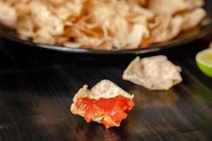 Close up Hand hold chip dip tomato salsa with plate with taco, nachos chips and tomato dip. Spicy Nachos  on rustic wooden background photo