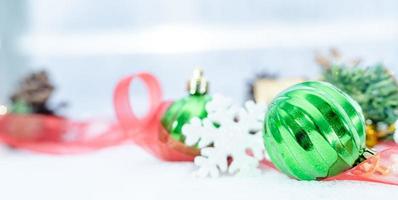 navidad de invierno - bolas de navidad con cinta en la nieve, concepto de vacaciones de invierno. bolas verdes de navidad, bolas doradas, decoraciones de pino y copos de nieve en el fondo de la nieve foto