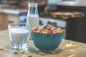 Tazón de coloridos cereales y leche para niños aislado en una mesa de madera con espacio de texto foto