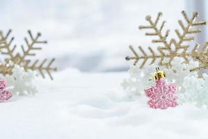 navidad de invierno - copos de nieve de navidad en la nieve, concepto de vacaciones de invierno. decoraciones de copos de nieve blancos y dorados en el fondo de la nieve foto