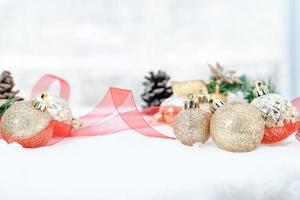 navidad de invierno - bolas de navidad con cinta en la nieve, concepto de vacaciones de invierno. bolas rojas de navidad, bolas doradas, decoraciones de pino y copos de nieve en el fondo de la nieve foto