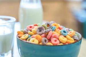 Tazón de coloridos cereales y leche para niños aislado en una mesa de madera con espacio de texto foto