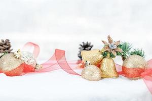 navidad de invierno - bolas de navidad con cinta en la nieve, concepto de vacaciones de invierno. bolas rojas de navidad, bolas doradas, decoraciones de pino y copos de nieve en el fondo de la nieve foto