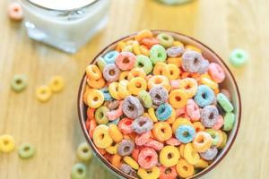 Tazón de coloridos cereales y leche para niños aislado en una mesa de madera con espacio de texto foto