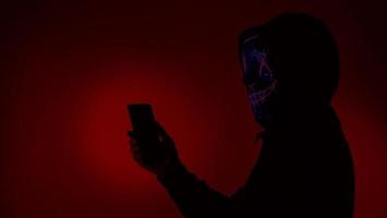 Digital security Concept. Anonymous hacker with mask holding smartphone hacked. photo