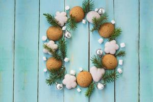 Christmas wooden background with tree branches, gingerbread and marshmallows photo
