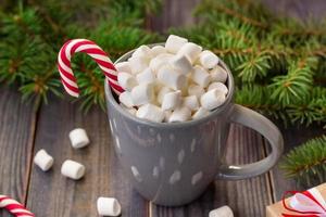 Hot coffee chocolate with marshmallow on rustic wooden table background, candy canes gift boxes fir tree photo