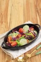 Healthy Vegetable Salad of Fresh Cherry Tomato, Cucumber, Onion, Purple Cabbage, Lettuce, and Lemon Dressing on Black Bowl. photo