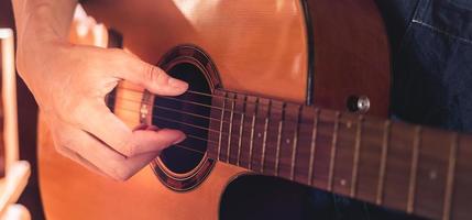 primer plano de las manos y los dedos de un músico masculino tocando una guitarra acústica. instrumento de guitarra musical para recreación o relajación concepto de pasión por el hobby. foto