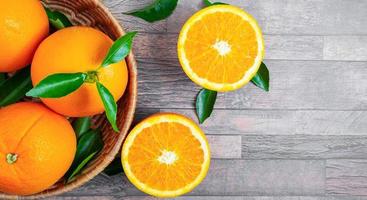 Top view of fresh orange fruit in baskets and halved orange fruit on the wooden background. photo