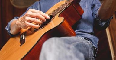 primer plano de las manos y los dedos de un músico masculino tocando una guitarra acústica. instrumento de guitarra musical para recreación o relajación concepto de pasión por el hobby. foto