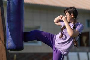 niña golpeando saco de arena. entrenamiento de boxeo muay thai. niña sana golpeando en el saco de boxeo. concepto de entrenamiento de boxeo, ejercicio, ejercicio físico, deporte foto