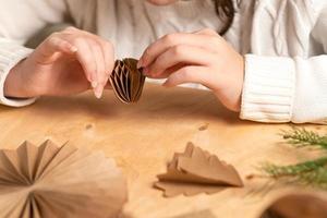 girl makes Christmas tree decorations out of paper with her own hands. step 5. step-by-step instruction photo