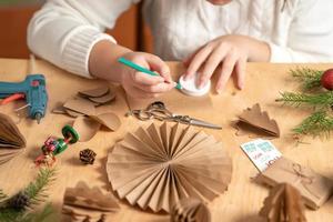 girl makes Christmas tree decorations out of paper with her own hands. step 1. step-by-step instruction photo