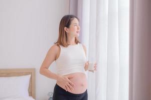 Young Asian woman standing in bedroom holding a glass of fresh milk photo