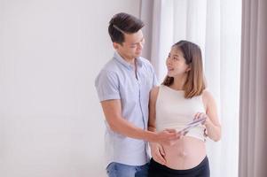 una familia asiática, padre y madre están viendo una película de ultrasonido de un niño en el útero de su madre que se acerca felizmente al momento del parto foto