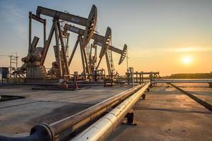 Oil field site, in the evening, oil pumps are running, The oil pump and the beautiful sunset of pumping unit in the evening. photo