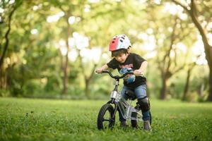 bangkok tailandia - 09 de octubre de 2016 feliz niño alegre montando una bicicleta en el parque en la naturaleza foto