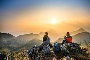 couple hiking at sunset mountain with heavy backpack golden hour for photography photo